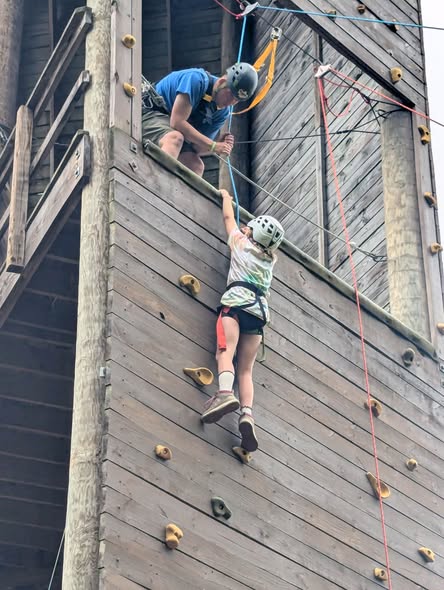 A scout climbing at Camp Mountaineer with support from camp staff