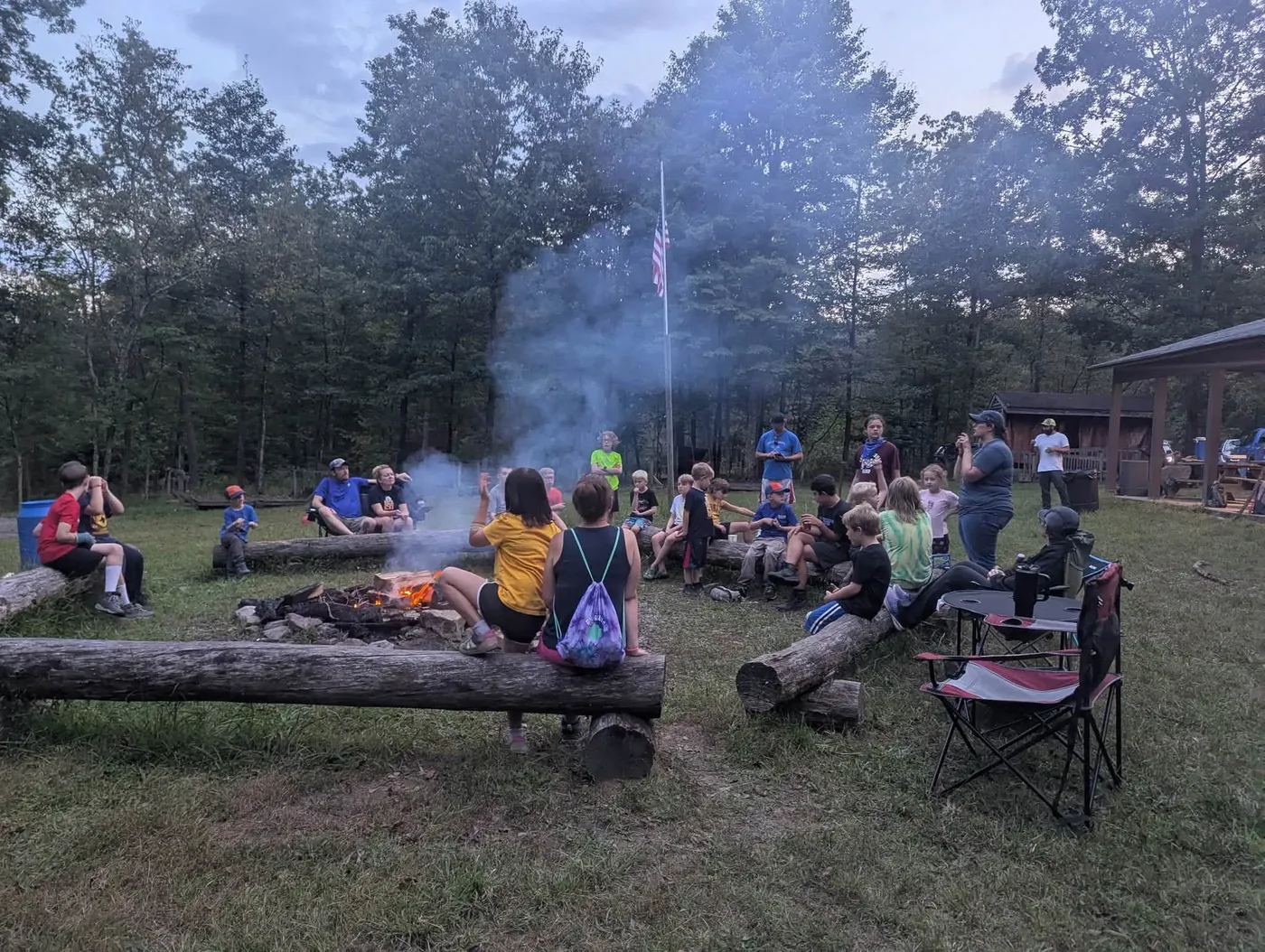 Scouts and families gathered around a campfire during a fall family campout