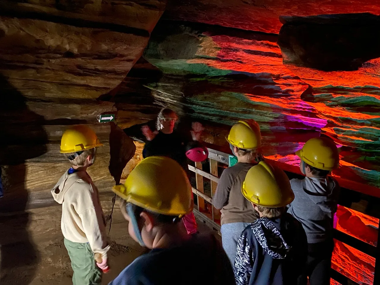 Scouts observing colorful lighting on layered cave rock
