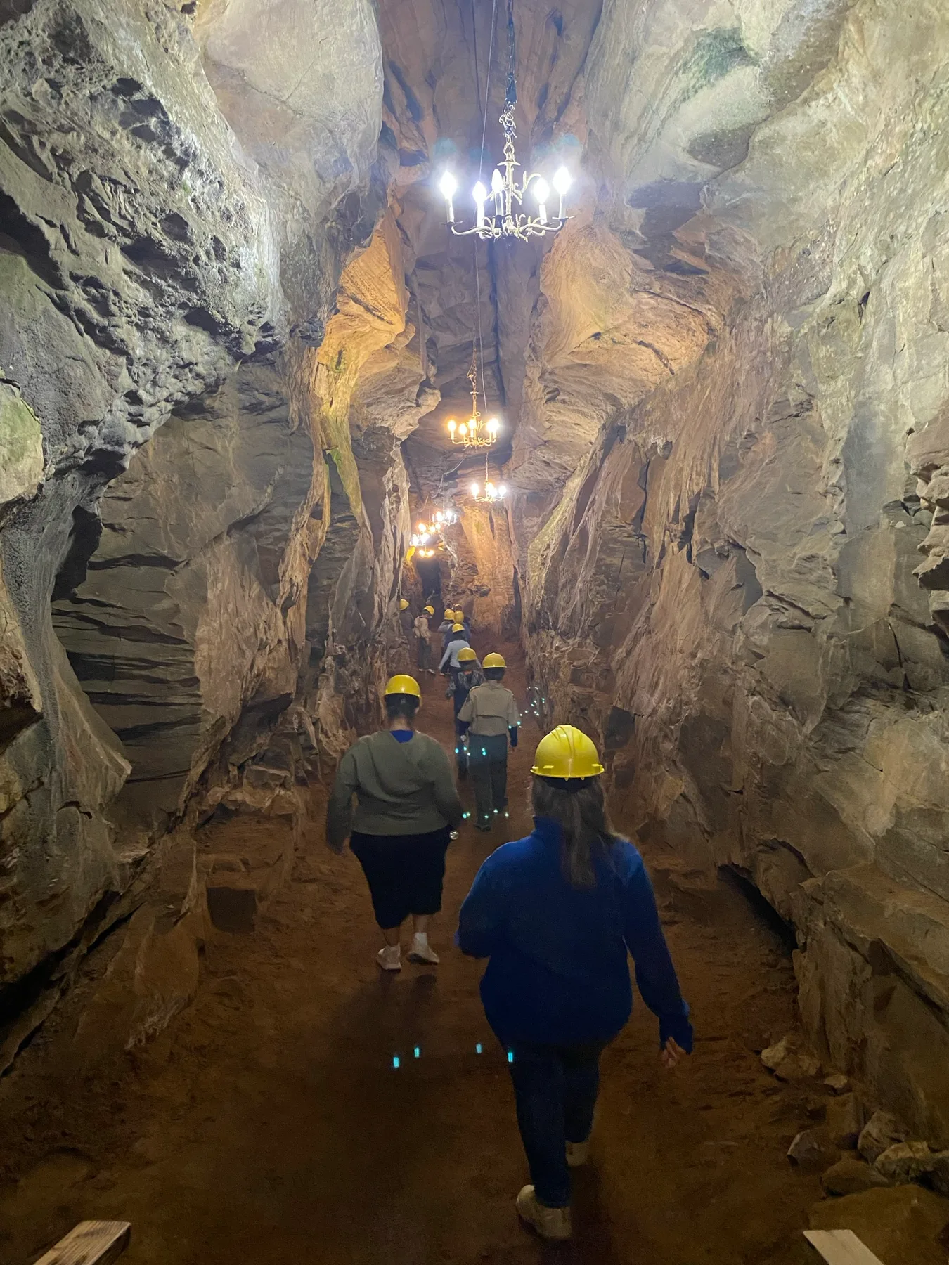 Scouts wearing helmets as they walk through a tall rock passage at Laurel Caverns