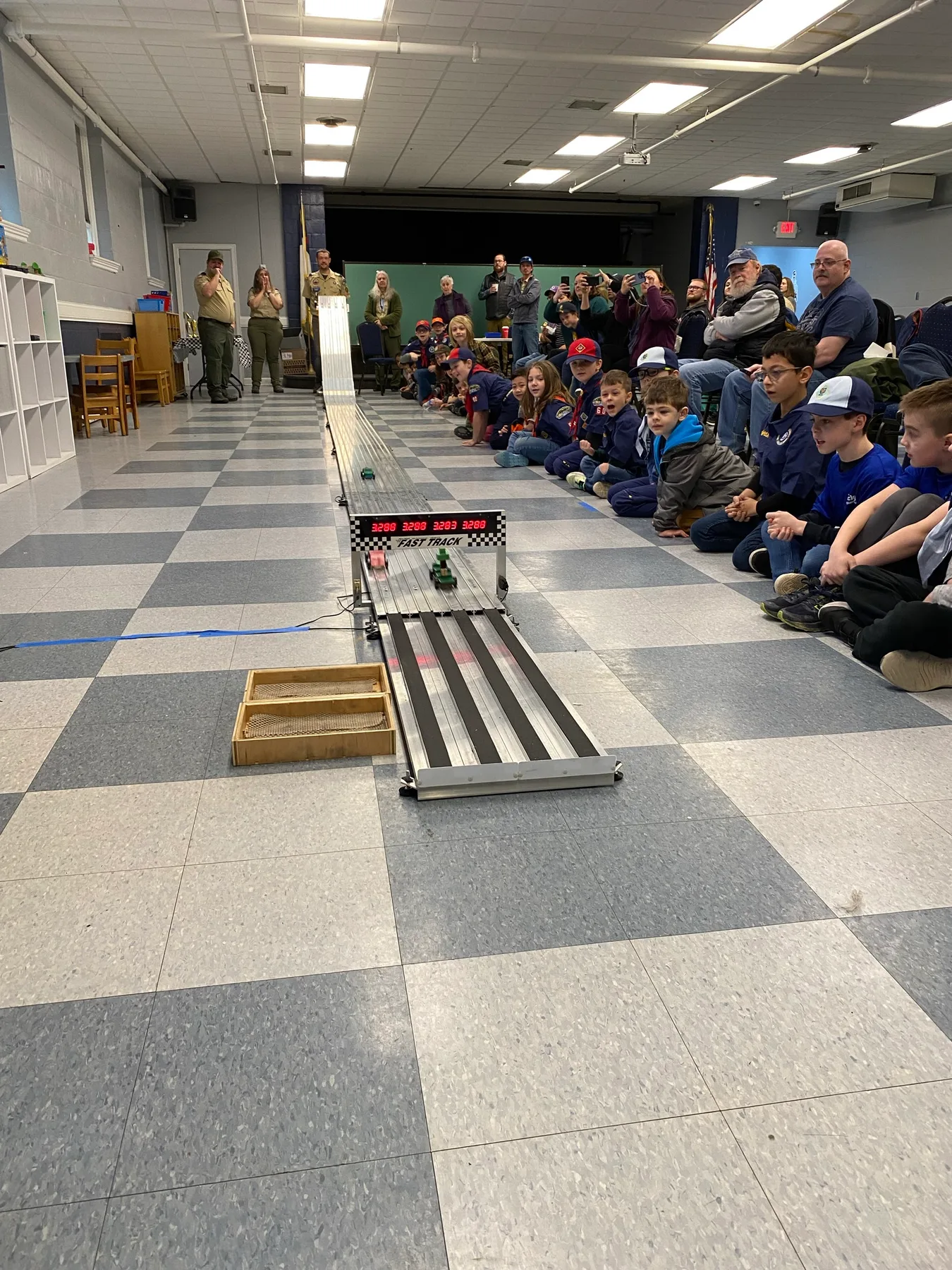 Pinewood Derby cars crossing the electronic finish line as scouts cheer