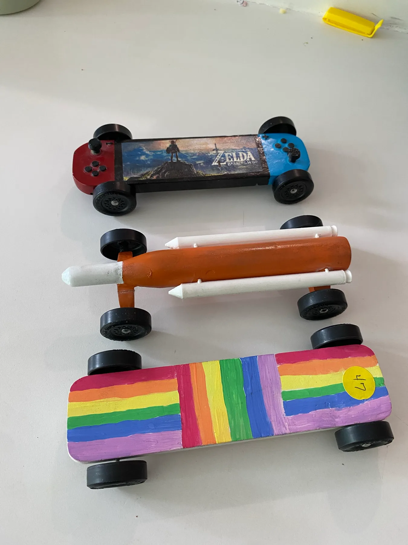 Three colorful handmade Pinewood Derby cars
