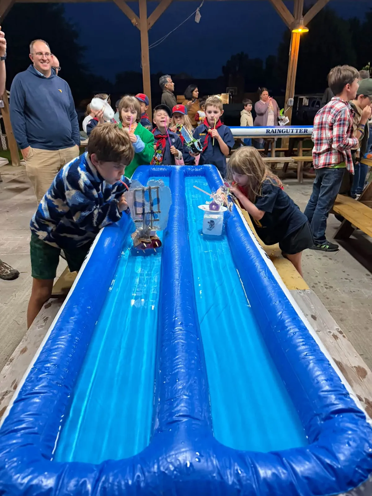 Scouts racing handmade boats in inflatable water lanes at the Raingutter Regatta